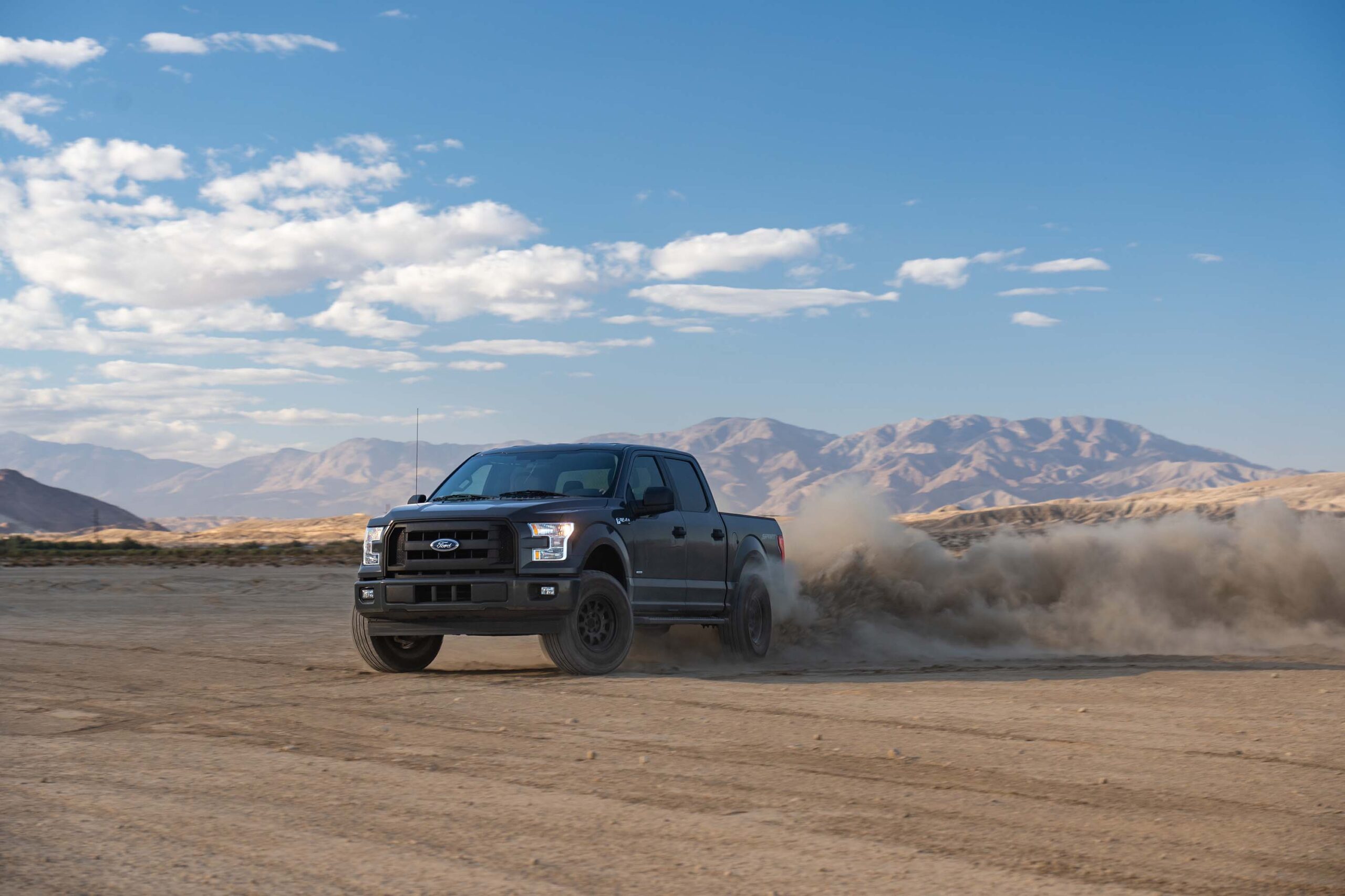 Black SUV in sandy terrain with mountains in background